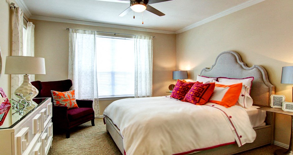Spacious bedroom with walk-in closet and ceiling fan at Tuscany Apartments in Houston.