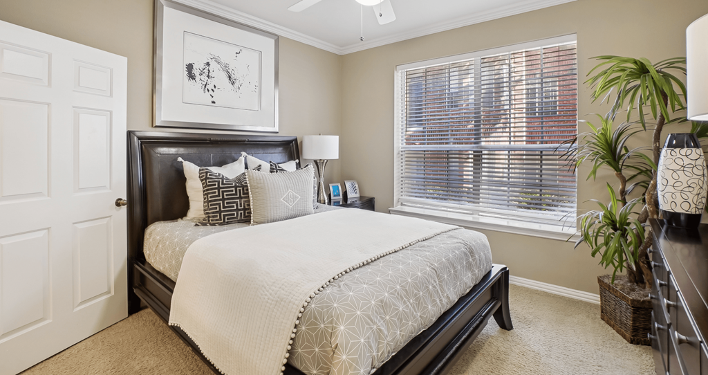 A bedroom with a large bed and a picture on the wall.