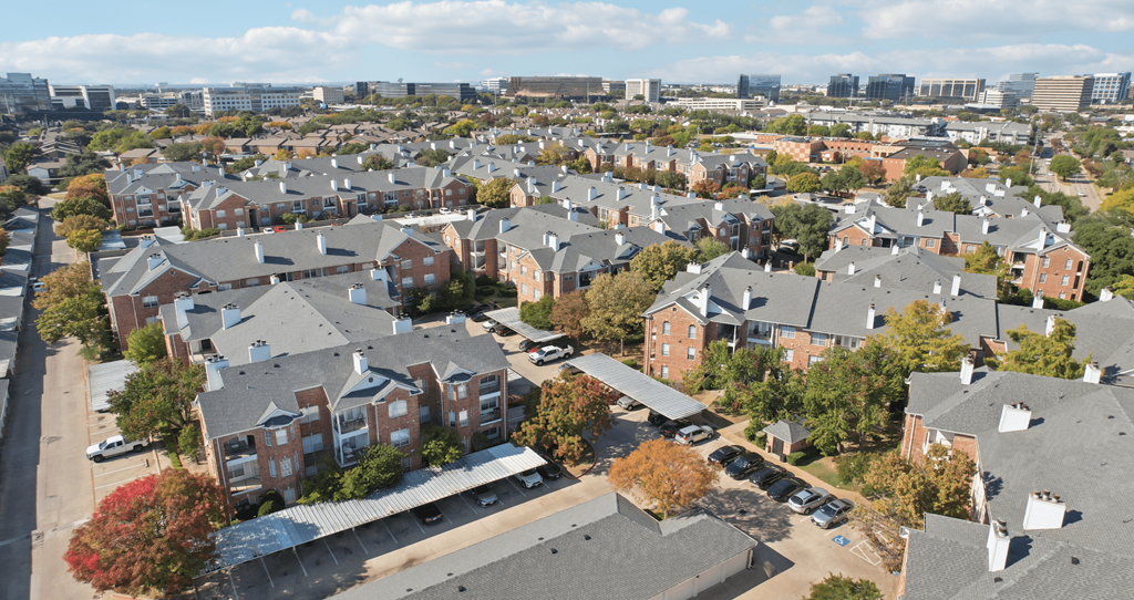 A large apartment complex with a parking lot in front.