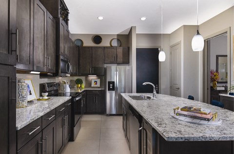 a large kitchen with marble counter tops and dark cabinets
