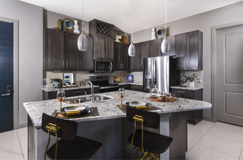 Luxury apartments with granite countertops, stainless steel appliances, built-in wine rack, kitchen island, and porcelain tile floor at Xenia Apartments in Golden Valley, Minnesota