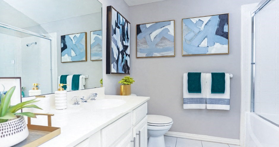 Spacious bathroom with tile floors, gray colored walls, glass enclosed shower and oval soaking tub, and lots of counter space at The Dorchester Apartments in Dallas Texas