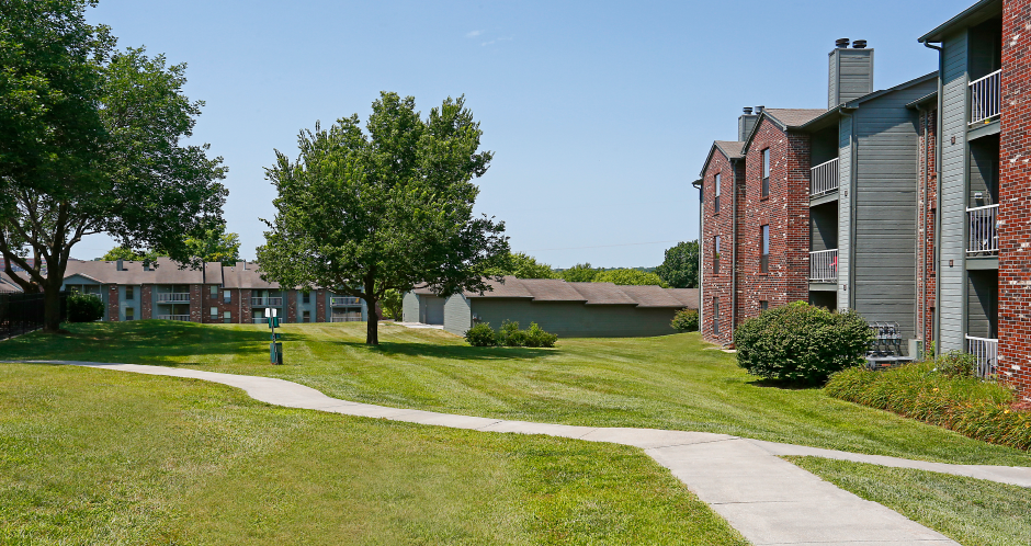 Green and red brick exterior, beautiful landscaping, scenic views, lots of trees, and spacious balconies at LionsHead Apartments in Omaha, Nebraska