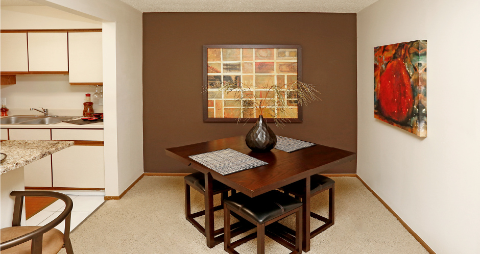 Spacious dining room with colored feature wall, and bright white kitchen with tile floor at LionsHead Apartments in Omaha, Nebraska