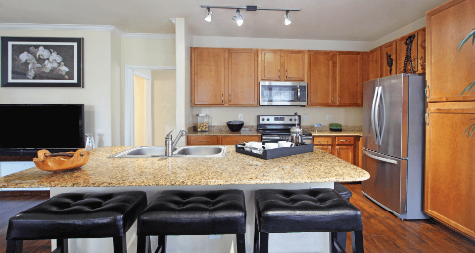 Luxury apartments in Houston with spacious kitchen and dining room with granite countertops, kitchen island, stainless steel appliances, oversized windows, lots of natural light, and hardwood floors.