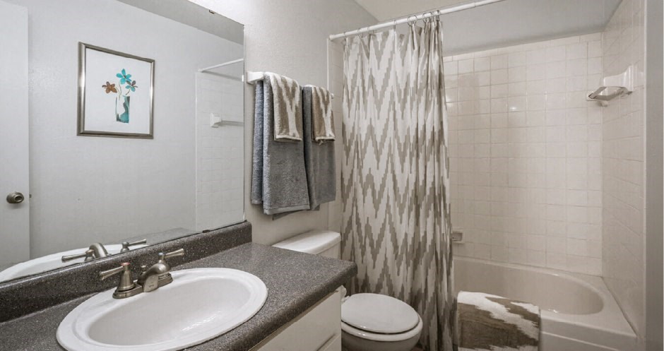 Spacious bright white bathroom with extra cabinet and storage space at Woodlake on the Bayou Apartments in Houston.