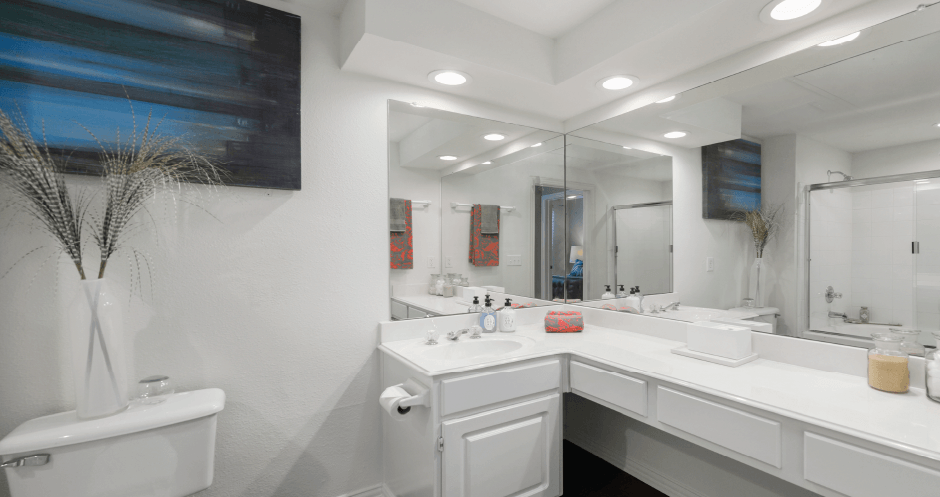 Spacious bathroom with oval soaking tub with glass enclosure, cultured marble vanity, glass shower, and built-in vanity at Tuscany Park Apartments in Houston.