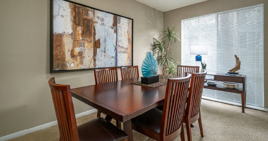 Spacious dining area with oversized windows, lots of natural light, and gray painted walls at Woodlake on the Bayou Apartments