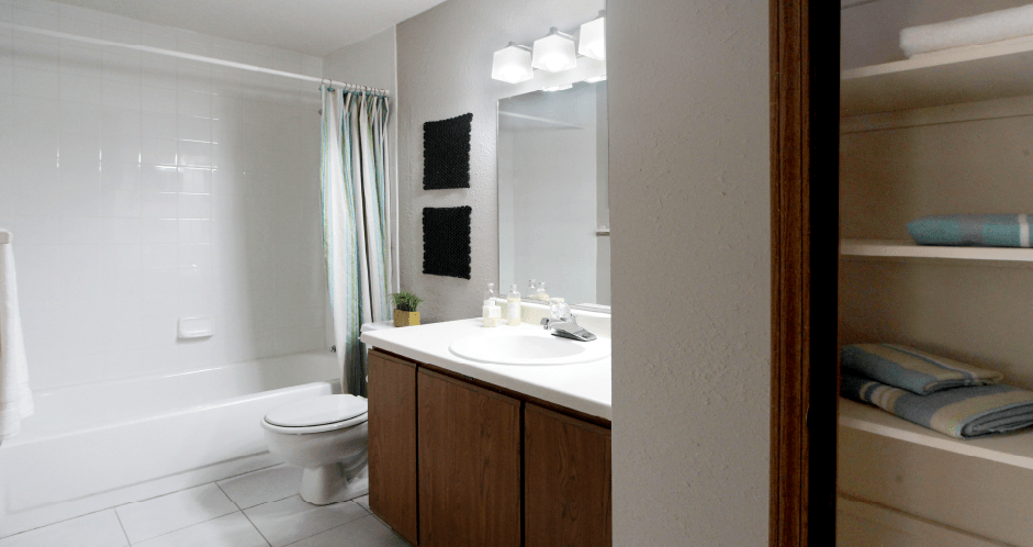 Spacious bathroom with lots of cabinet space, tiled floor, tiled shower, extra cabinet space, and gray wall color at The Vanderbilt Apartments in Omaha, Nebraska