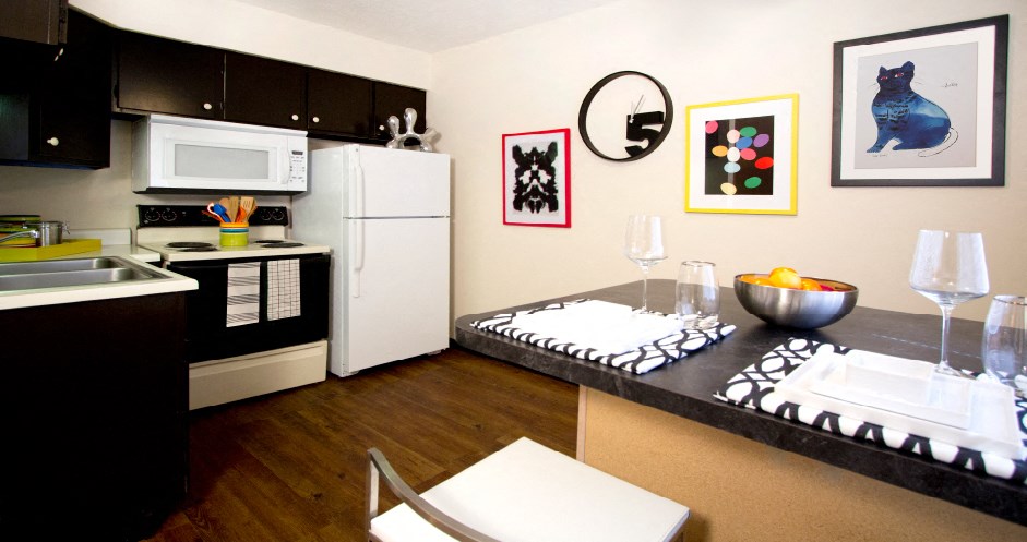Kitchen with wood pattern floors, black kitchen cabinets, and spacious dining room at Kensington Woods Apartments in Omaha, Nebraska