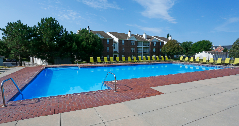 Huge swimming pool with spacious sundeck, poolside lounge chairs, beautiful landscaping, and scenic views at The Vanderbilt Apartments in Omaha, Nebraska