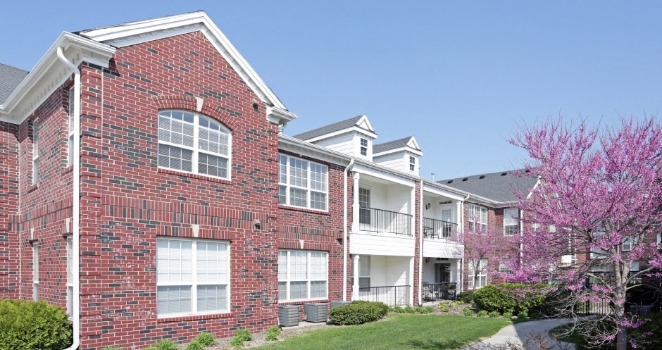 Luxury apartments with red brick exteriors, beautiful landscaping, and scenic views at Rockledge Oaks Apartments in Lincoln, Nebraska