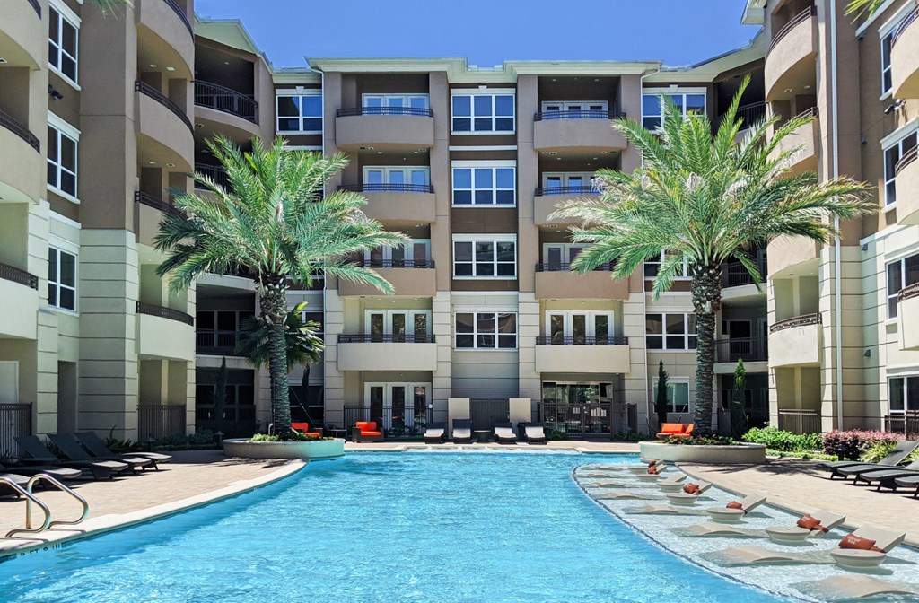 Luxury apartments with resort-style pool and palm trees, fountains, lap lane, and pool-side lounge chairs at Tuscany Walk Apartments in Houston