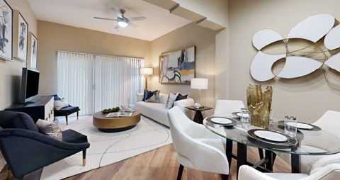A modern living room with a glass dining table and white chairs.