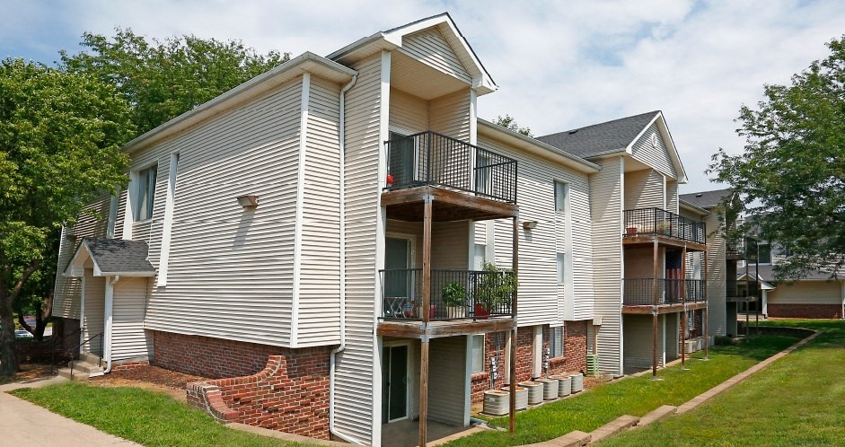 a white apartment building with balconies and a sidewalk