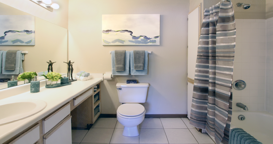 Spacious bathroom with extra cabinet space, built-in vanity, and tiled floor and shower at Tanglewood Apartments in Lincoln, Nebraska