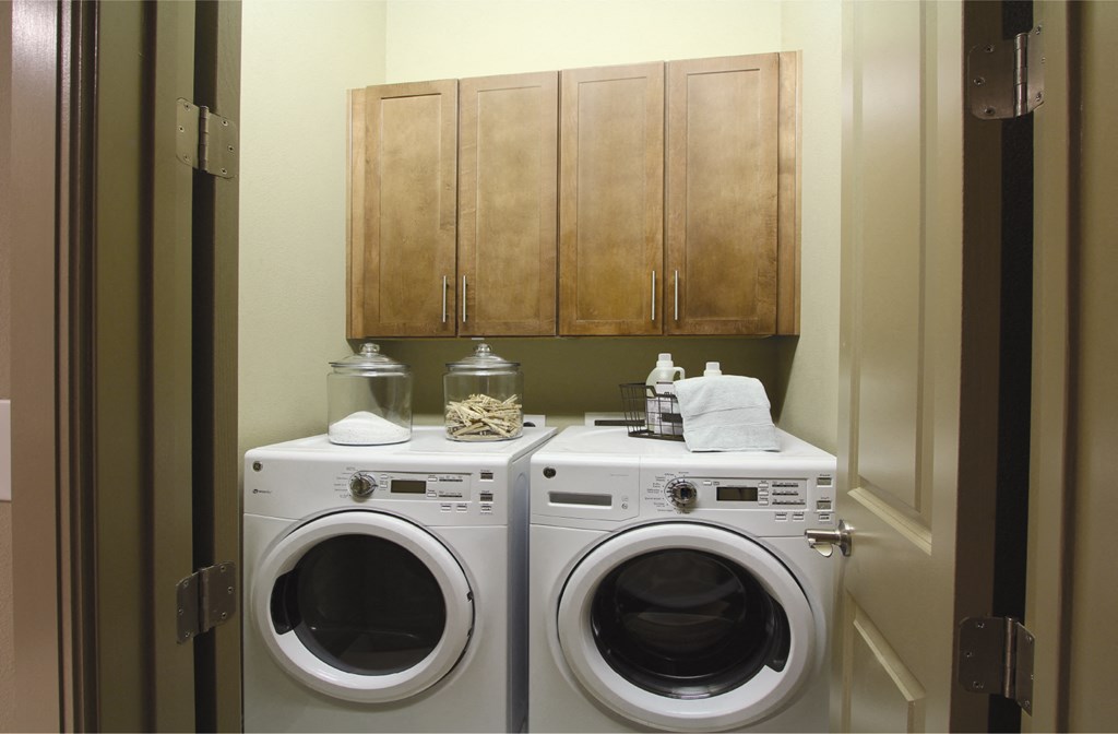Luxury apartments with full size front loading washer and dryer with cabinet space above at Tuscany Walk Apartments in Houston.