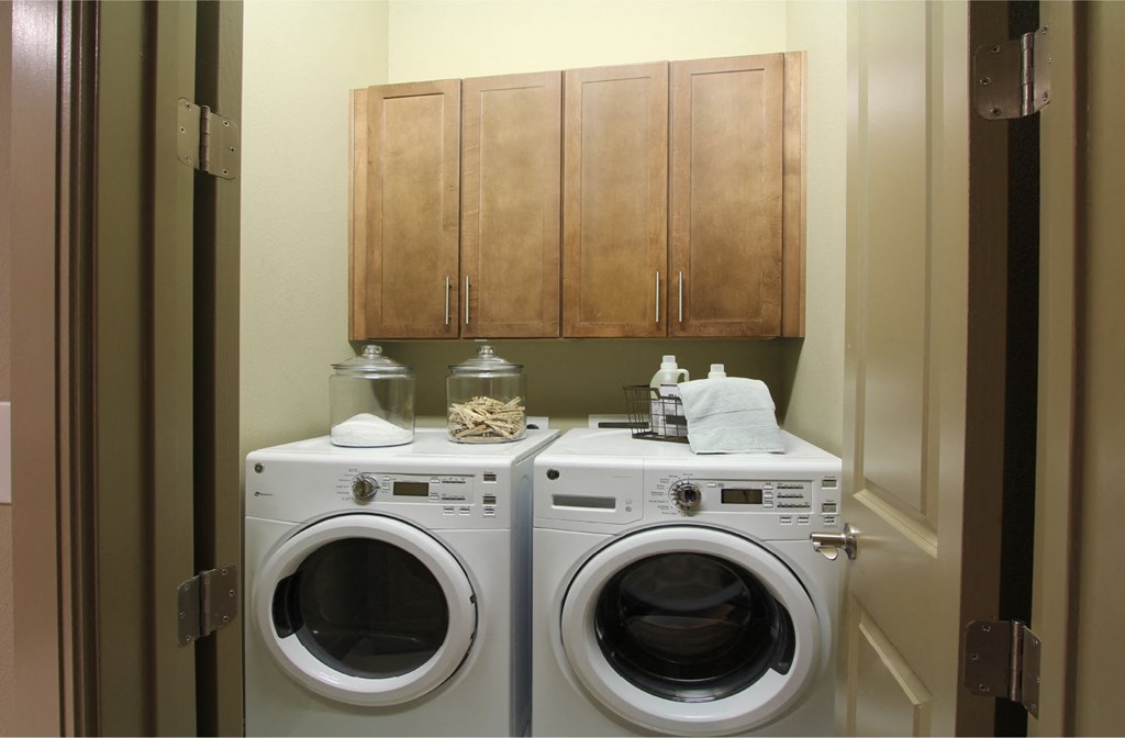 Luxury apartments with full size front loading washer and dryer with cabinet space above at Tuscany Walk Apartments in Houston.