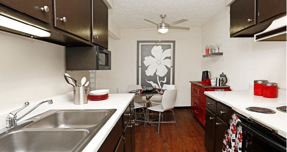 a kitchen with a sink and a table and a ceiling fan