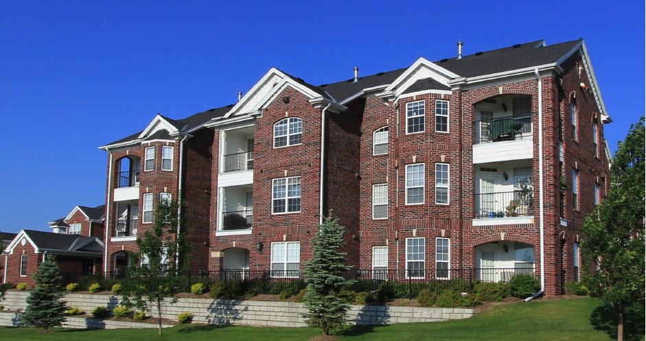 Luxury apartments with spacious balcony, red brick exterior, and beautiful landscaping at Rockledge Oaks Apartments in Lincoln, Nebraska