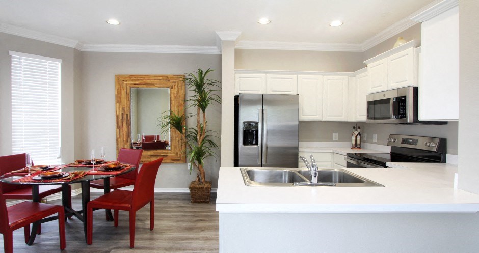 Luxury apartments with spacious u-shaped kitchen, white cabinets, oversized windows, spacious dining room, stainless steel appliances, and bright white kitchen at Rockledge Oaks Apartments in Lincoln, Nebraska