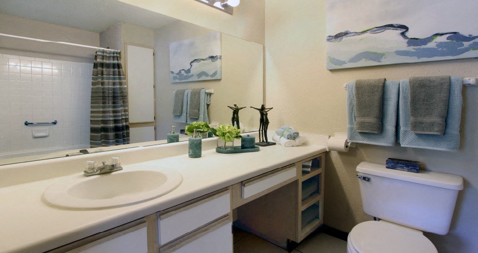 Spacious bathroom with extra cabinet space, built-in vanity, and tiled floor and shower at Tanglewood Apartments in Lincoln, Nebraska