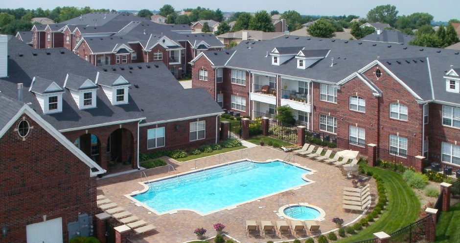 Luxury apartments with red brick exteriors, swimming pool, pool-side lounge chairs, beautiful landscaping, and scenic views at Rockledge Oaks Apartments in Lincoln, Nebraska