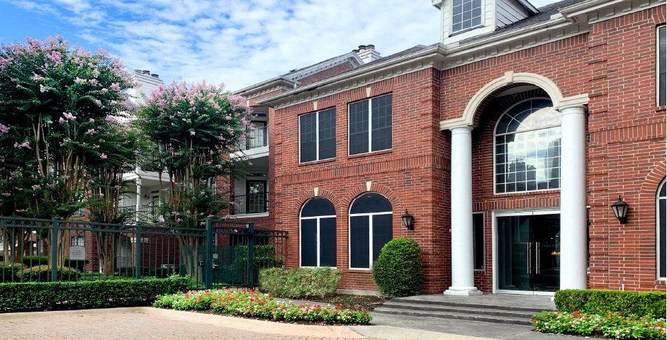 Luxury apartments with brick exteriors and lush landscaping at Tuscany Apartments in Houston.
