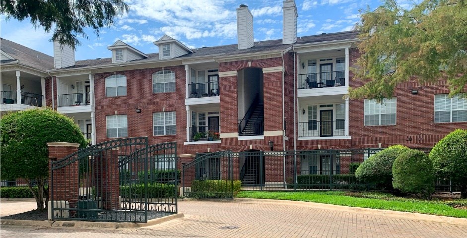 Gated community luxury apartments with brick exteriors, private outside storage, French doors, and lush landscaping including beautiful chaste trees at Tuscany Apartments in Houston.