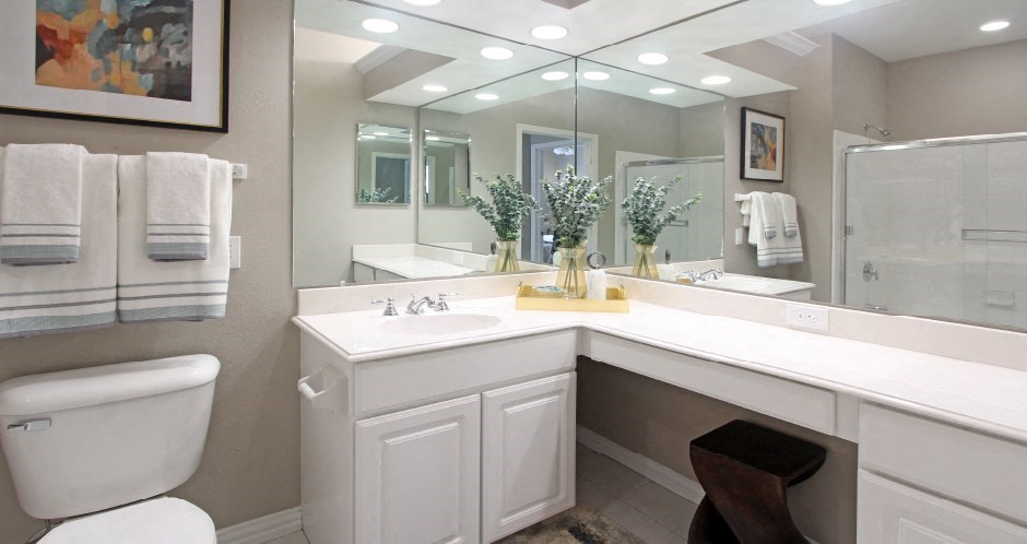 Luxury bathroom with tiled floors, glass shower, oval soaking tub, cultured marble vanity, and white cabinets in at Rockledge Oaks Apartments in Lincoln, Nebraska