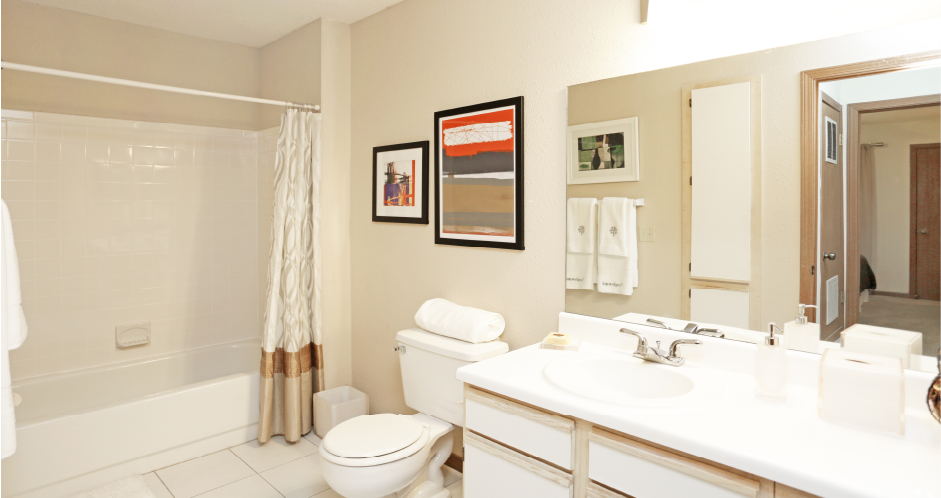 Spacious bathroom with extra cabinet space, linen closet, and tiled floor and shower at Tanglewood Apartments in Lincoln, Nebraska