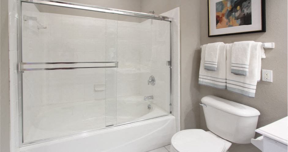 Luxury bathroom with tiled floors, glass shower, and oval soaking tub at Rockledge Oaks Apartments in Lincoln, Nebraska