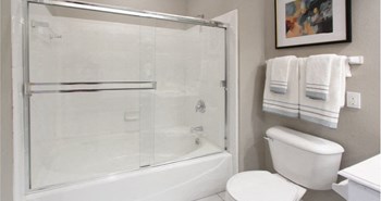 Luxury bathroom with tiled floors, glass shower, and oval soaking tub at Rockledge Oaks Apartments in Lincoln, Nebraska - Photo Gallery 21