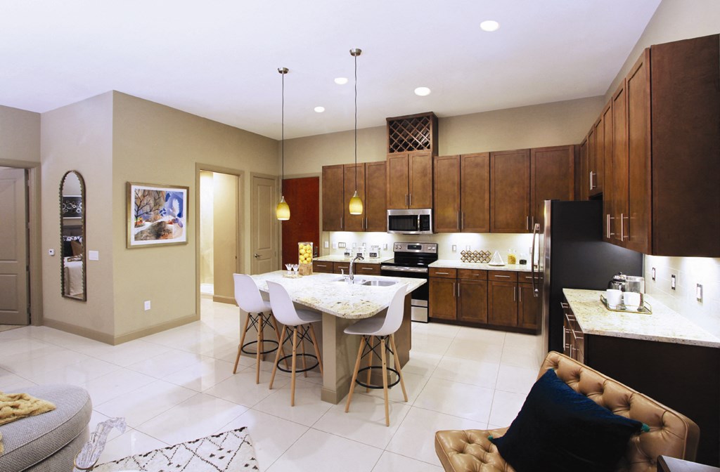 Luxury apartments with spacious kitchen and built-in wine rack, granite countertops, kitchen island, stainless steel appliances, and designer tile backsplash at Tuscany Walk Apartments in Houston Texas.