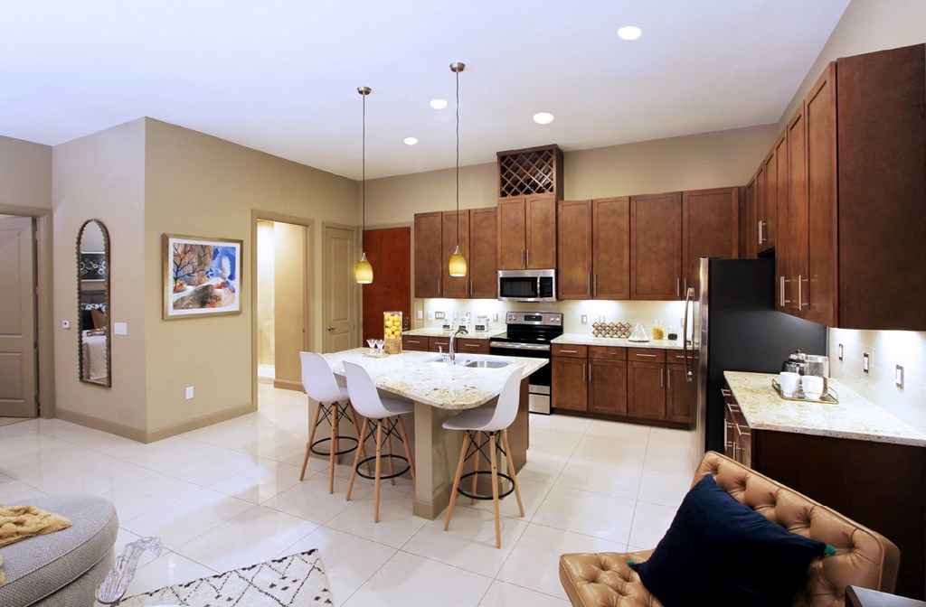 Luxury apartments with spacious kitchen and built-in wine rack, granite countertops, kitchen island, stainless steel appliances, and designer tile backsplash at Tuscany Walk Apartments in Houston Texas.