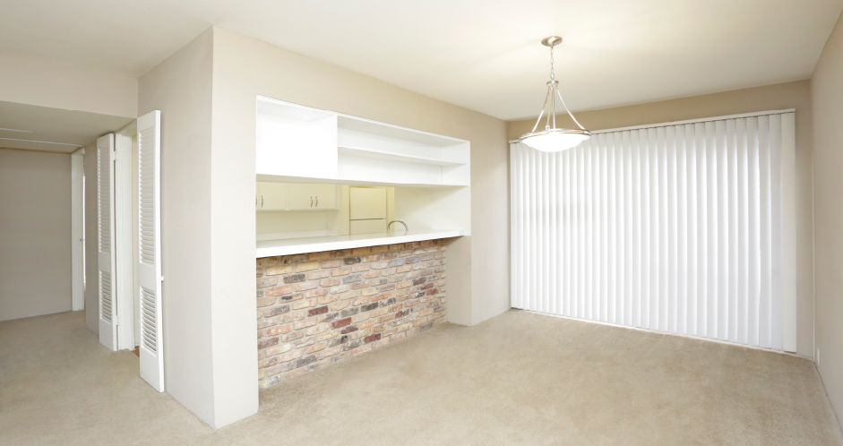 Spacious dining room with brick feature wall, built-in shelves, breakfast bar, and bright white kitchens at Plantation apartments near the Galleria in Houston.