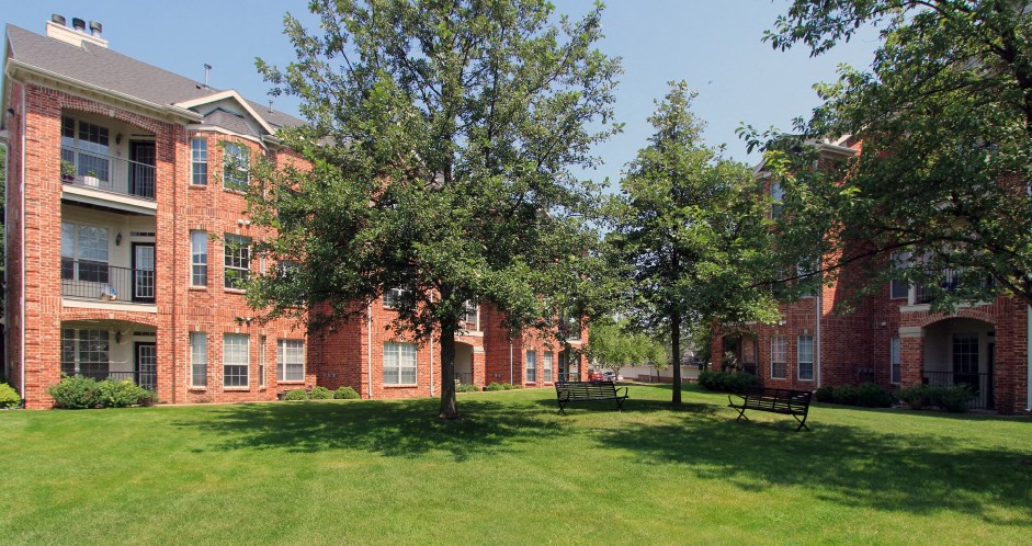 Luxury apartments with red brick exterior, lush landscaping, park-like setting, and scenic views at Lenox Village Apartments in Lincoln, Nebraska