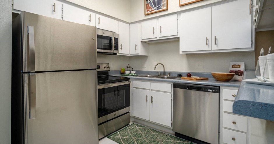 Kitchen with white cabinets, stainless steel appliances, and breakfast bar at Woodlake on the Bayou Apartments