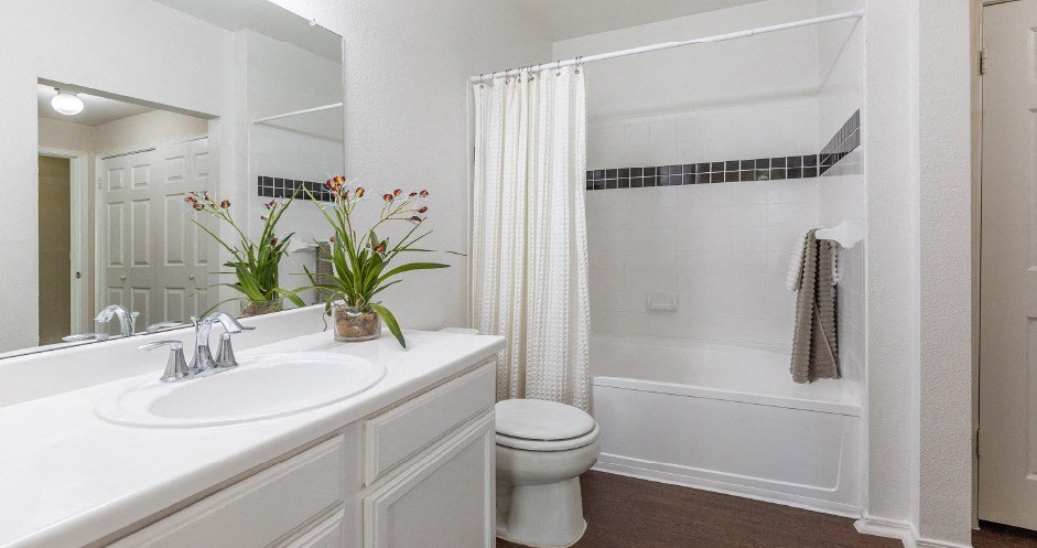 Spacious bright white bathroom with oversized garden tub and built-in vanity at Village on the Parkway Apartments