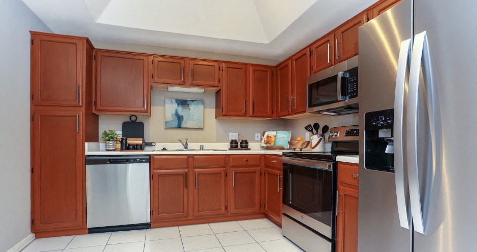 Spacious kitchen with stainless steel appliances, side-by-side refrigerator with water dispenser, recessed ceiling, and lots of cabinet space at The Dorchester Apartments in Dallas Texas