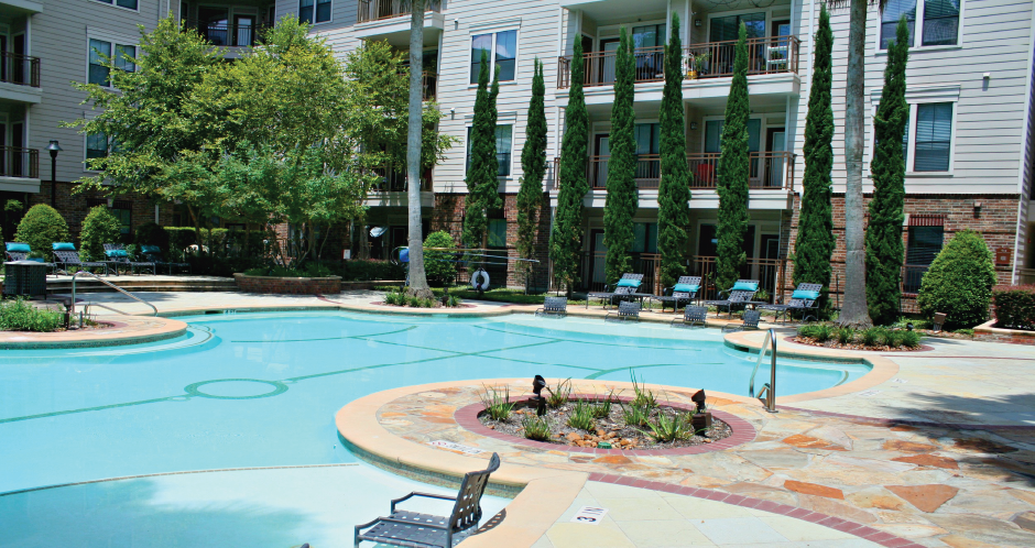 Luxury swimming pool with cabanas, poolside lounges, grilling stations, palm trees and beautiful landscaping at The Voss Apartments in Houston.