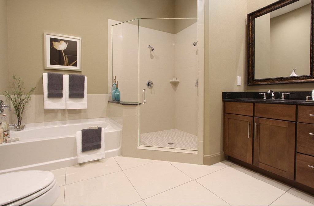 Spacious bathroom with oval soaking tub, separate shower with glass enclosure, and cultured marble vanity at Tuscany Walk Apartments in Houston