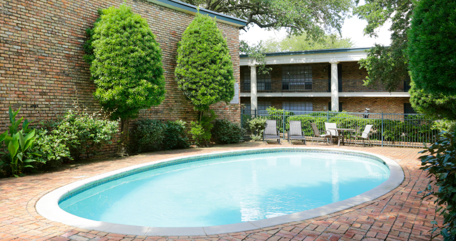 Apartments near the Galleria with multiple swimming pools, sun deck with poolside lounge chairs, brick exteriors and courtyard setting at Plantation apartments in Houston.