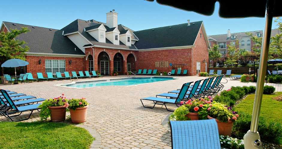 Luxury apartments with swimming pool, poolside lounge chairs, picnic area, grilling station, lush landscaping, and scenic views at Lenox Village Apartments in Lincoln, Nebraska