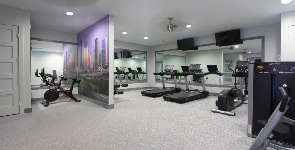 Newly remodeled Fitness Center open 24/7 with brand new Life Fitness equipment including 1 peloton bike, 4 resistance machines, 2 treadmills, 1 life cycle, 1 elliptical, full rack of free weights and dumbbells and water bottle refill fountain at Tuscany Apartments in Houston.