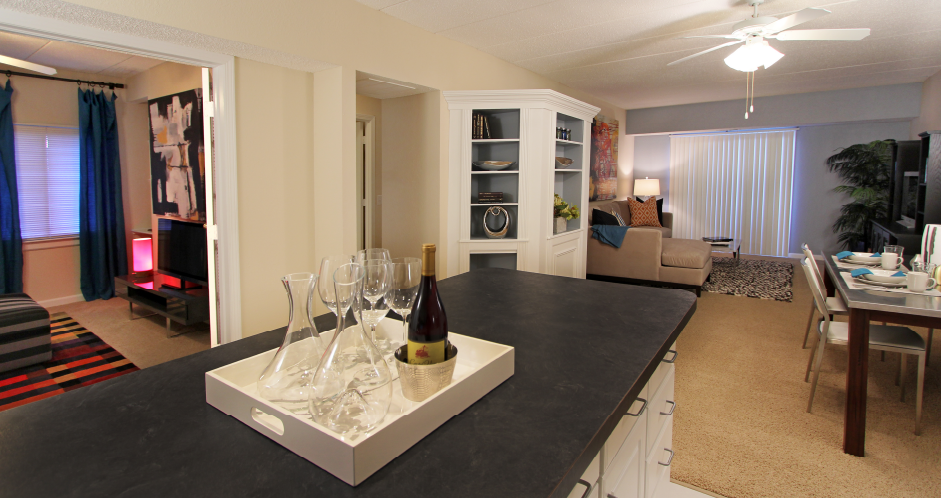 Spacious living room with colored feature wall, kitchen island, prep island, den or office space at Embassy Park Apartments in Omaha, Nebraska