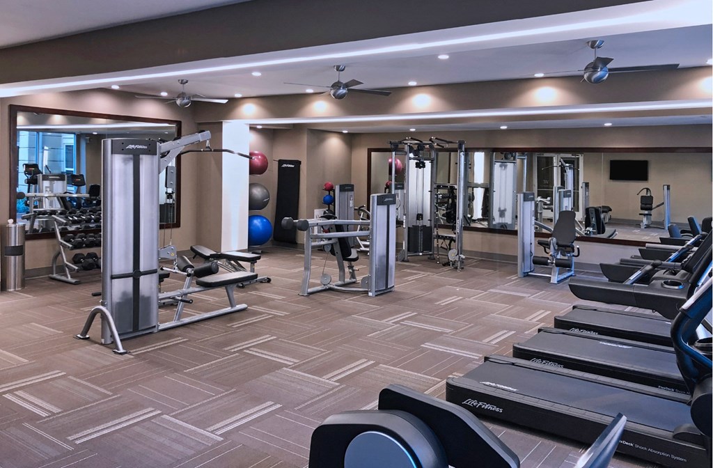 Luxury apartments with huge fitness center with multiple varieties of workout machines and equipment at Tuscany Walk Apartments in Houston Texas.