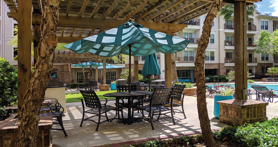 Luxury swimming pool with cabanas, poolside lounges, grilling stations, palm trees and beautiful landscaping at The Voss Apartments in Houston.