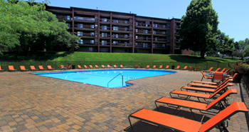 Resort-style saltwater pool with huge sun deck, poolside lounge chairs, and park-like setting with lots of trees and scenic views at Embassy Park Apartments in Omaha, Nebraska