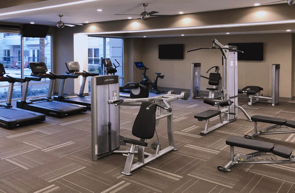 Luxury apartments with huge fitness center with multiple varieties of workout machines and equipment at Tuscany Walk Apartments in Houston Texas.